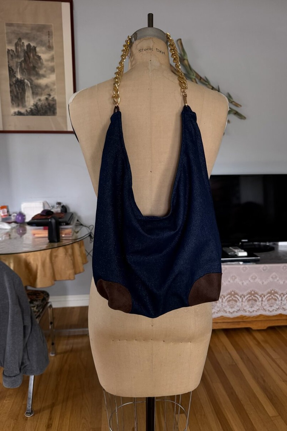 Indigo denim hobo bag on a vintage dress form, with a Chinese ink-wash mountain painting on the wall.